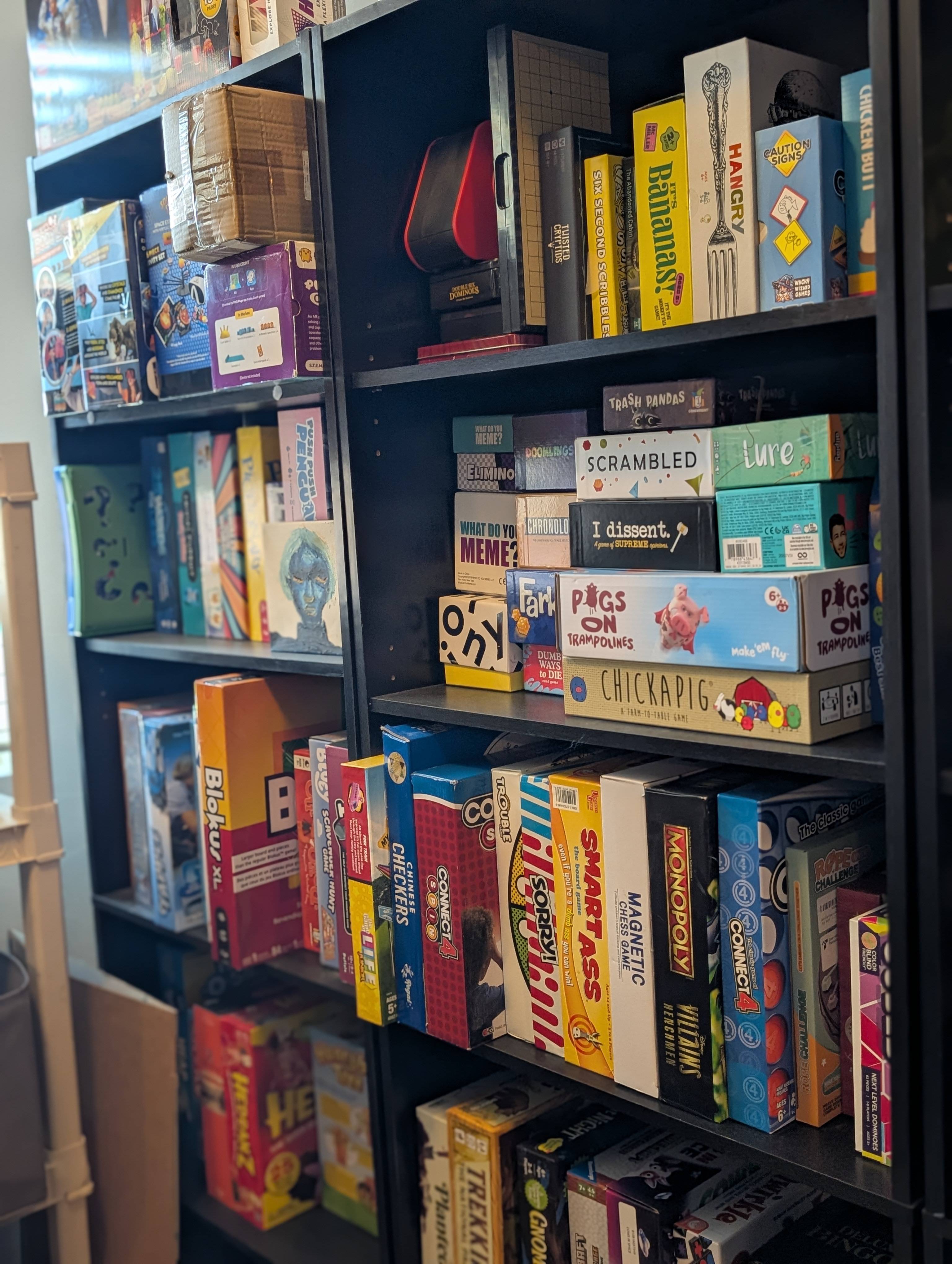 Shelves packed with board games like Bananas, Monopoly, Trouble, and Chickapig
